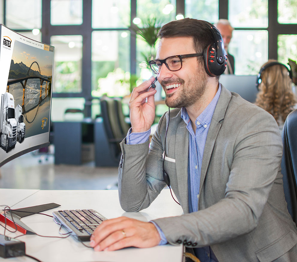 Un représentant du service clientèle parlant dans un casque, regardant un écran d’ordinateur.